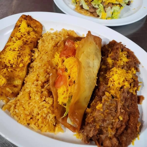 A Mexican combo plate with a cheesy enchilada, rice, a crispy taco, and refried beans.